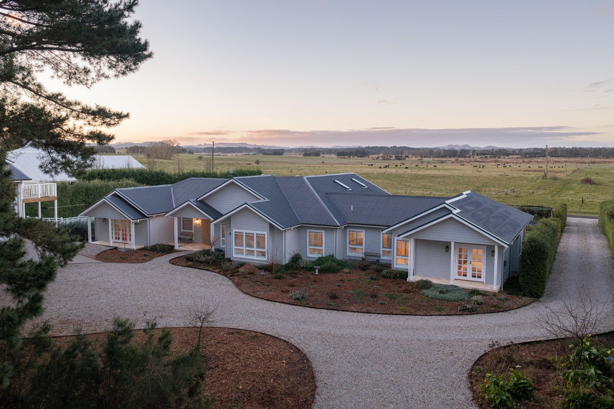 Birchgrove at dusk, the house held within its circular drive with the fields beyond.